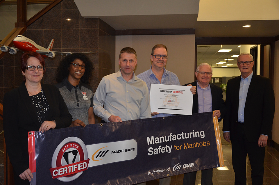 People holding a Manufacturing Safety for Manitoba banner