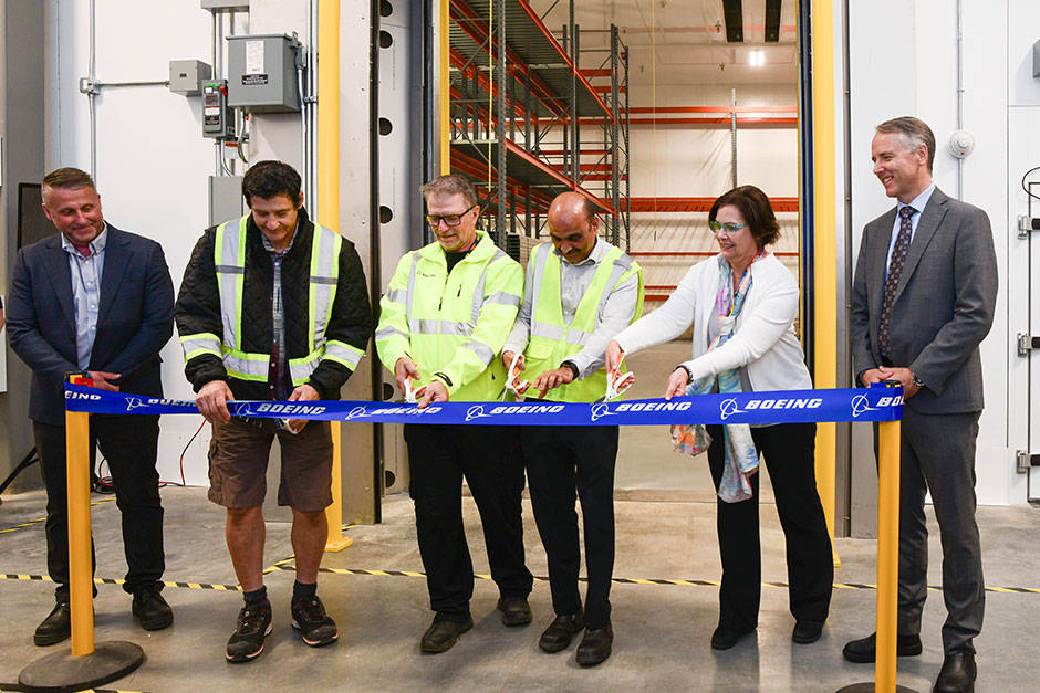 Boeing Winnipeg Facilities leader Brent Evans and Boeing Canada president Al Meinzinger look on as stores keepers Tony De Groot and Rick Delaine cut the ribbon with project manager Venkat Shenoy and site leader Teri Thompson to officially open the new freezer.