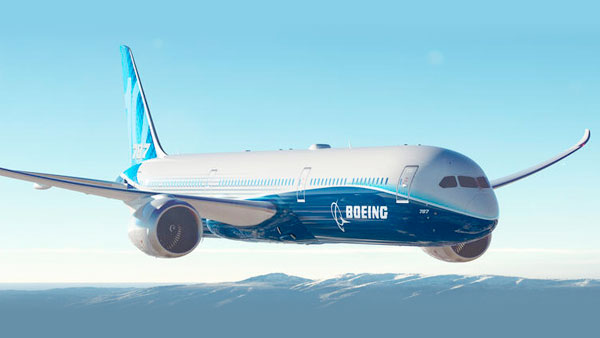 787 in flight over mountains in a cloudless sky